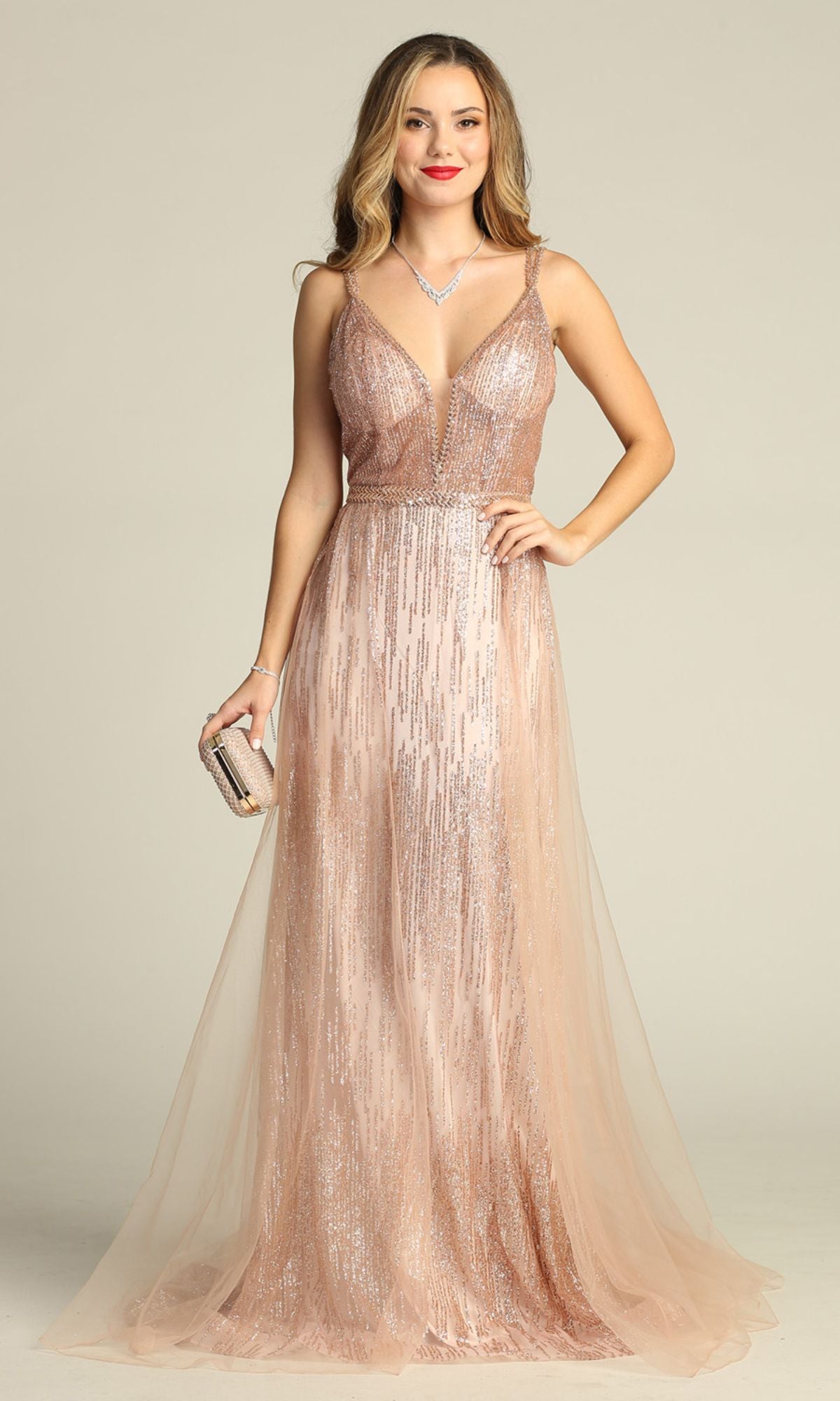 A woman wearing the Sheer-Waist Long Sequin Prom Dress (Chicas YG5021)—a sleeveless, blush pink gown with a deep V-neckline—holds a small clutch and stands against a plain light background.